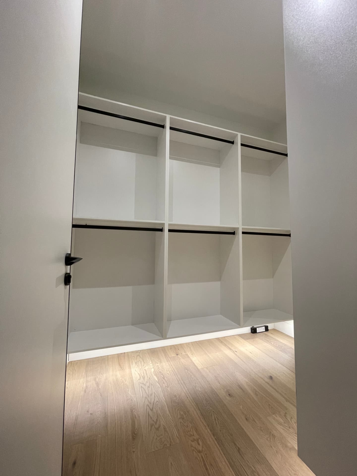 White floating closet system with black hanging rails and drawer fronts