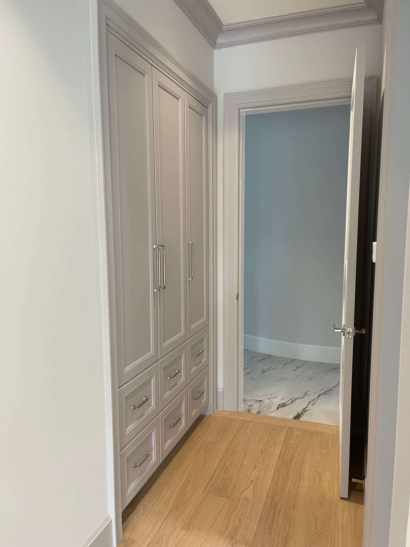 Custom grey built-in wardrobe with crown molding, drawer bank, hanging rails, and overhead cabinets