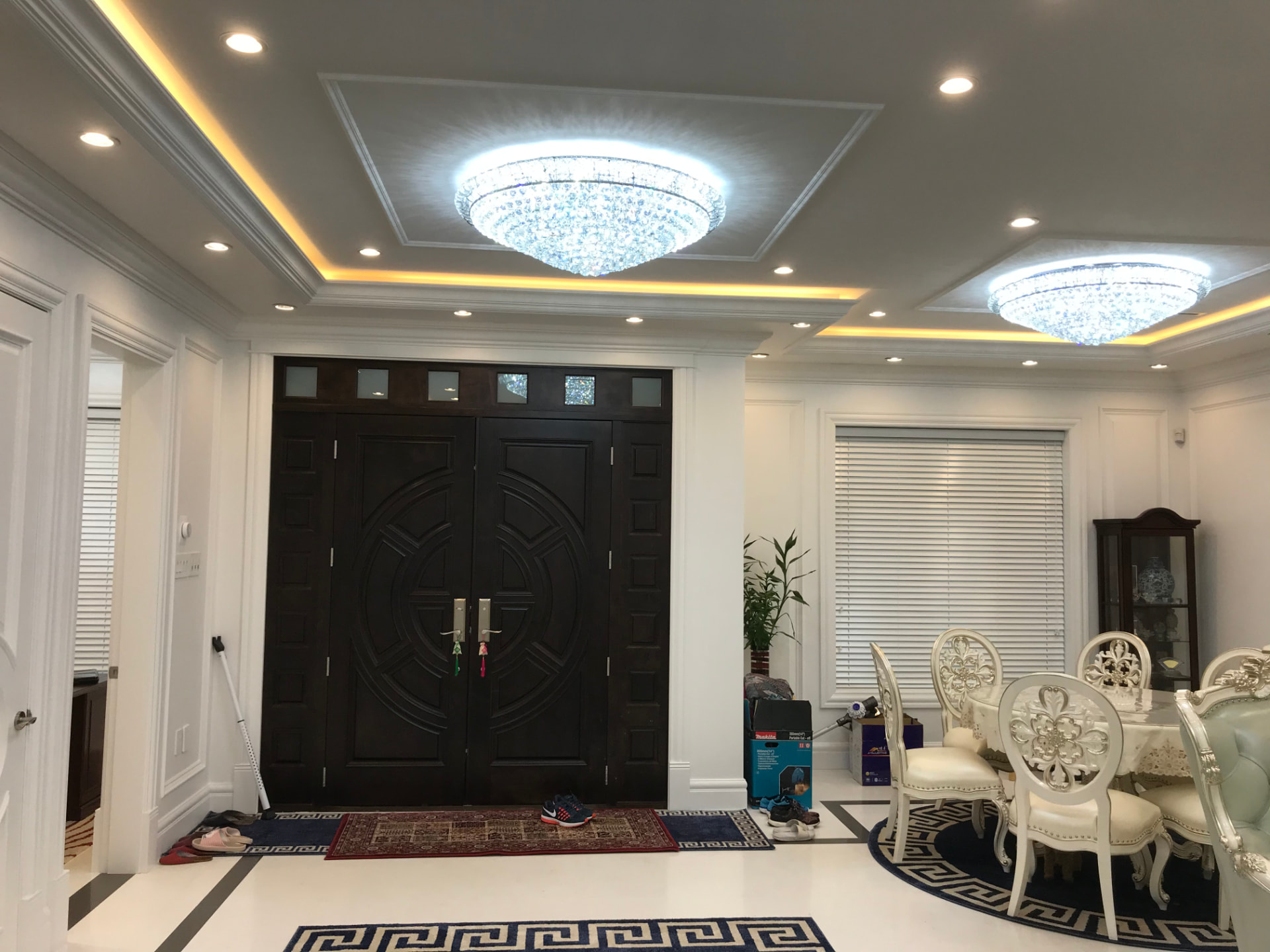 White wainscoting and panel moulding through a foyer, living room, bedroom, and staircase