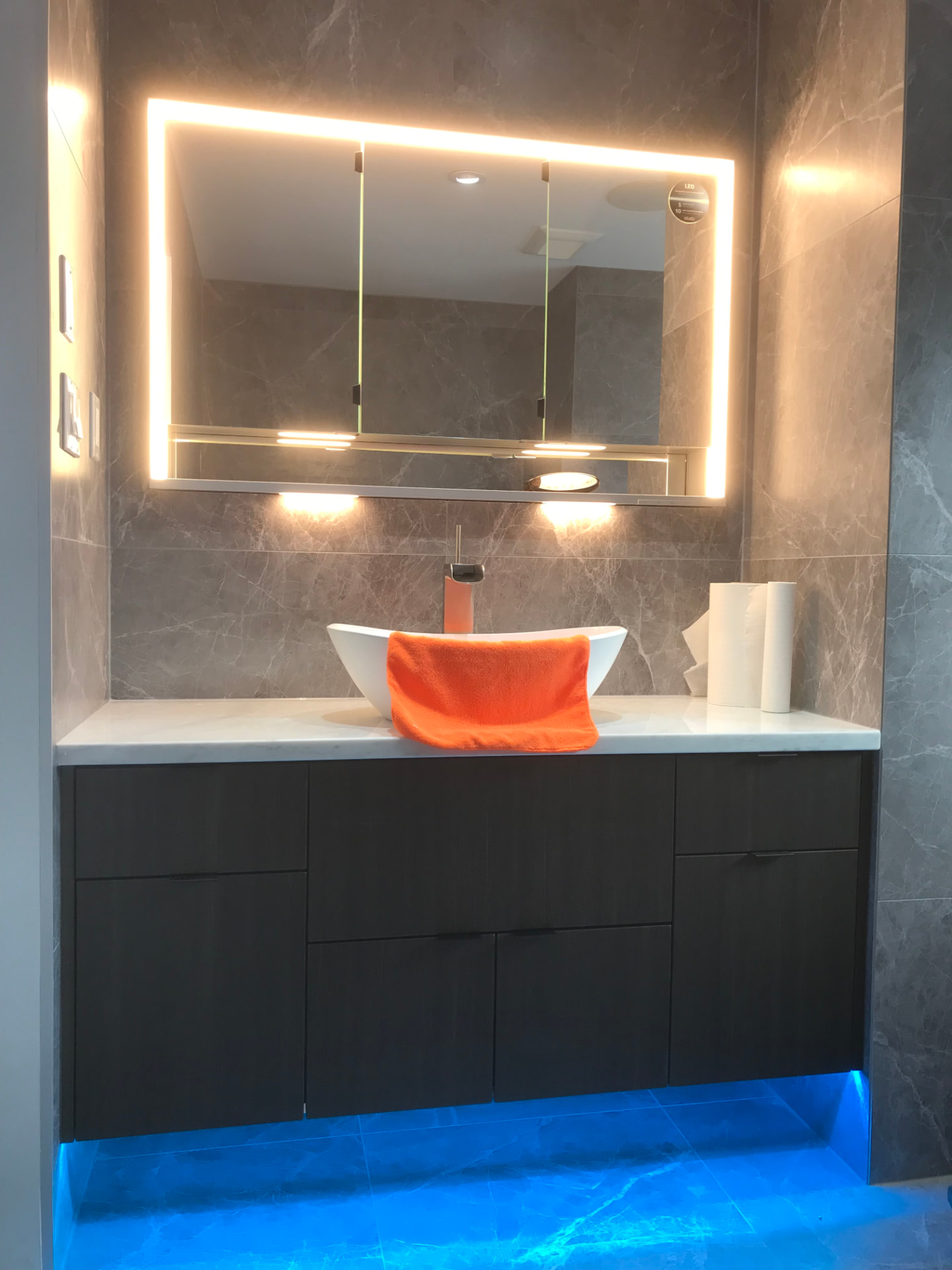 Charcoal floating bathroom vanity with marble counter and backlit mirror cabinet