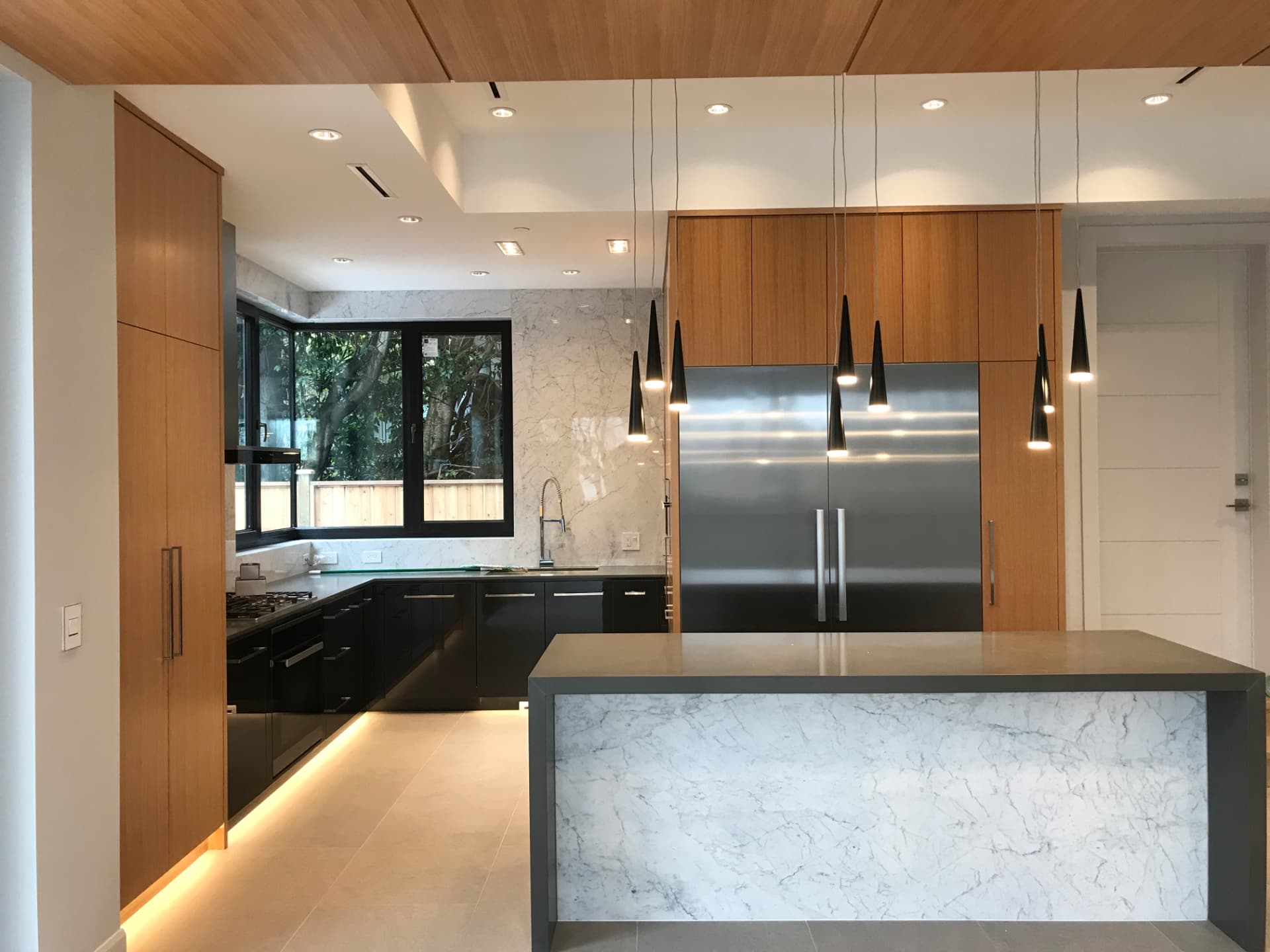 Modern walnut and marble custom kitchen with dark island and cone pendants