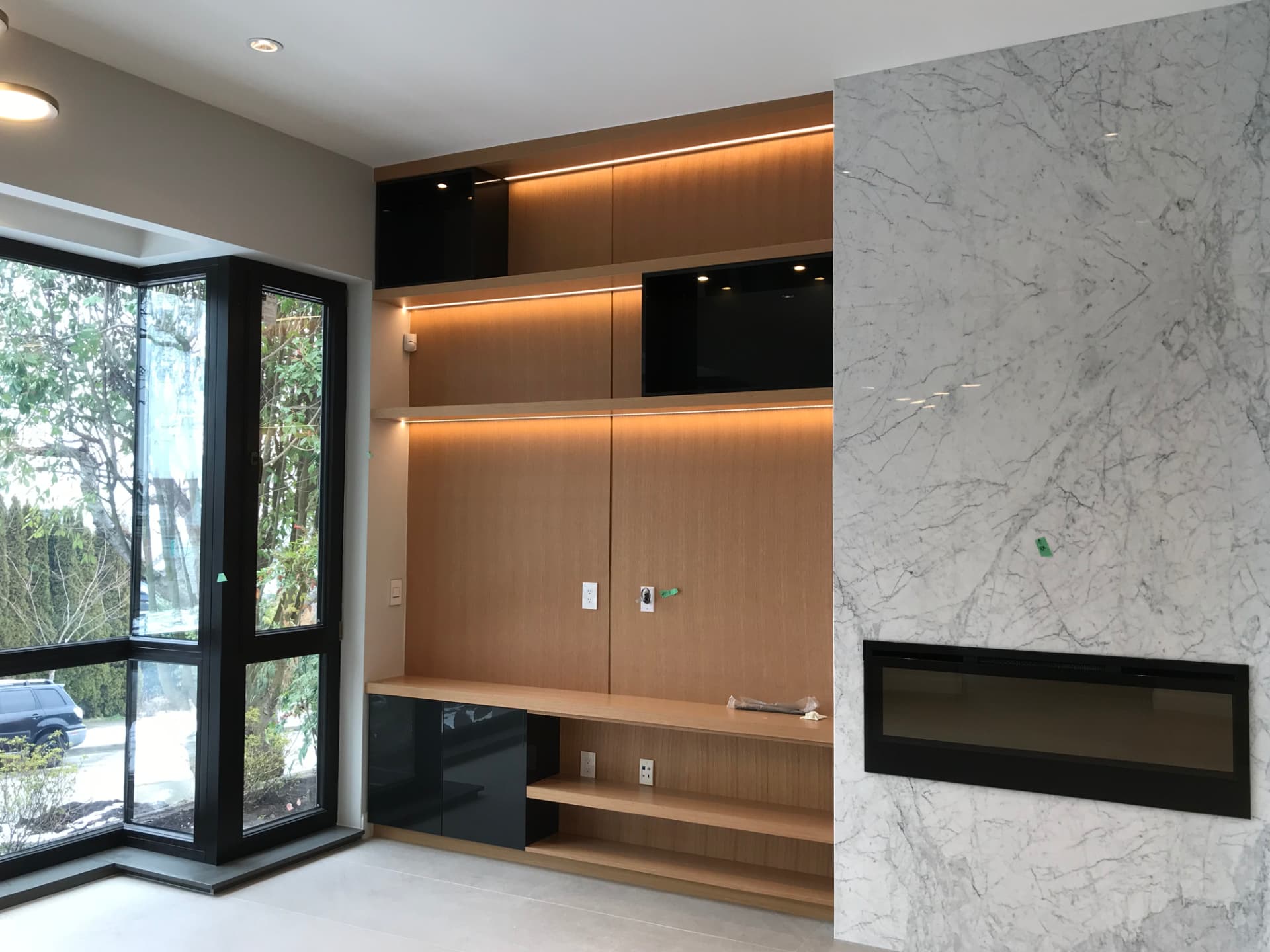 Custom wood living room millwork with floating shelves and a marble fireplace