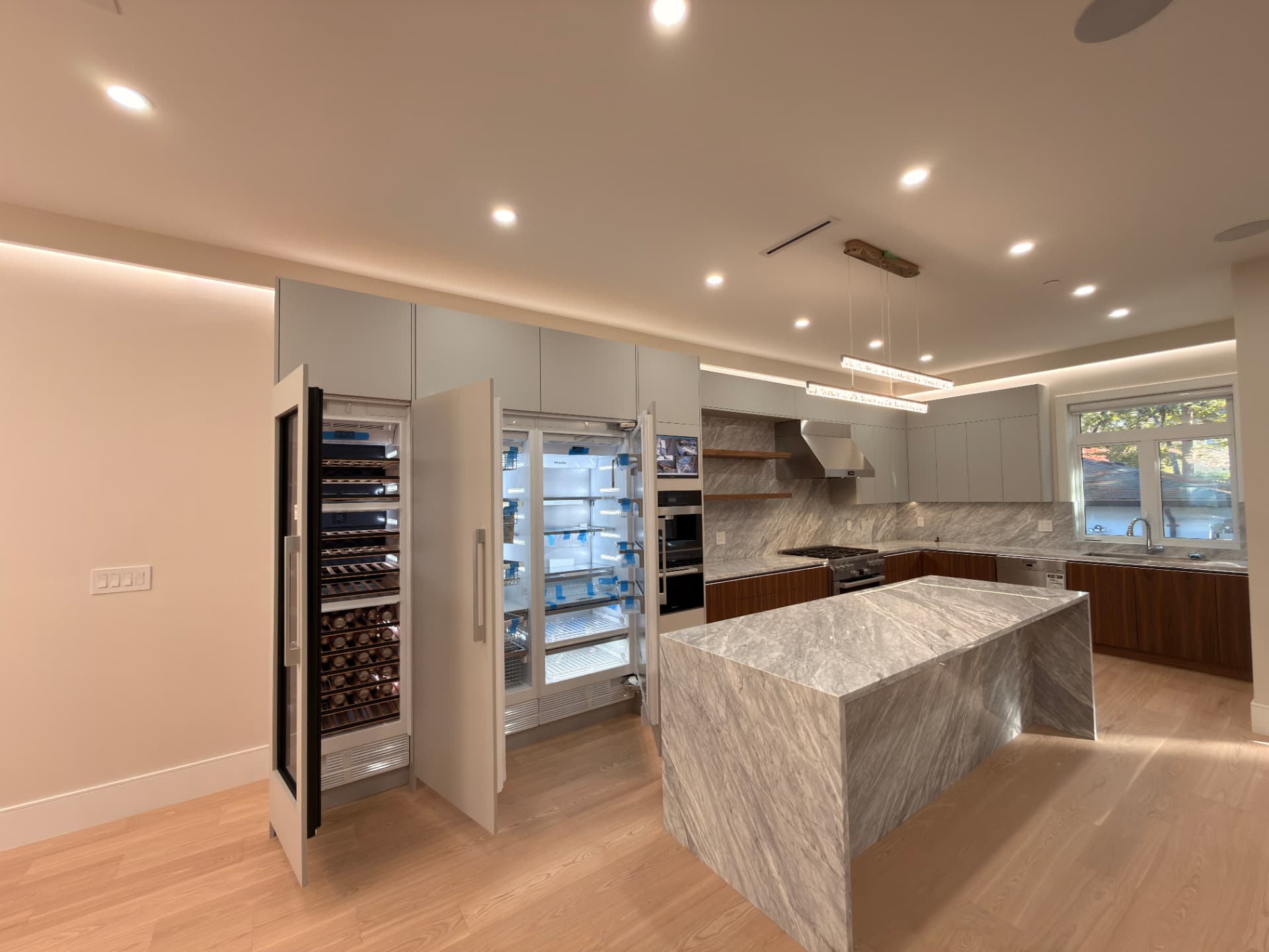 Custom grey and walnut kitchen with a marble island by A Plus Cabinets