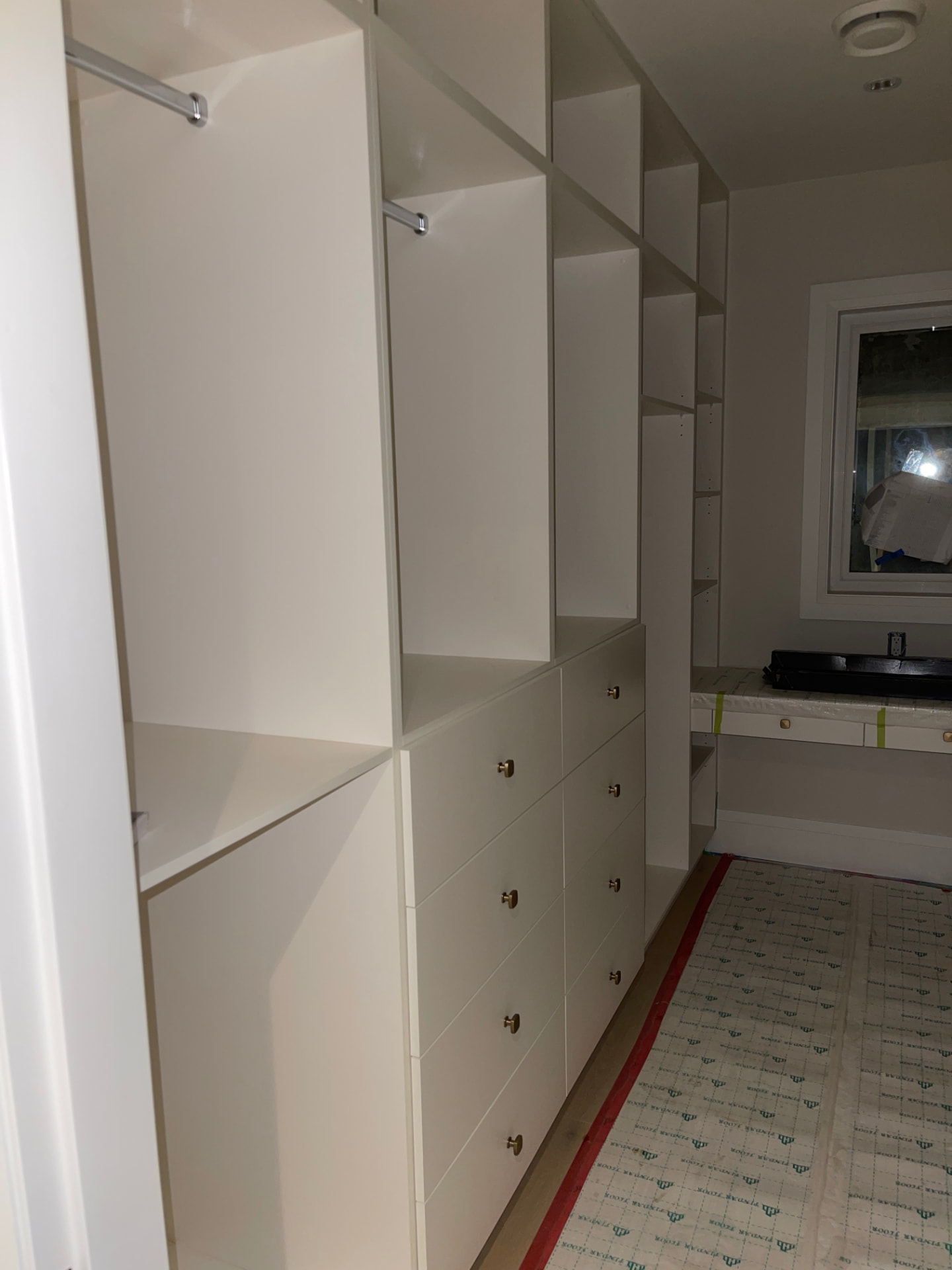 White built-in closet system with brass knobs and hanging rails