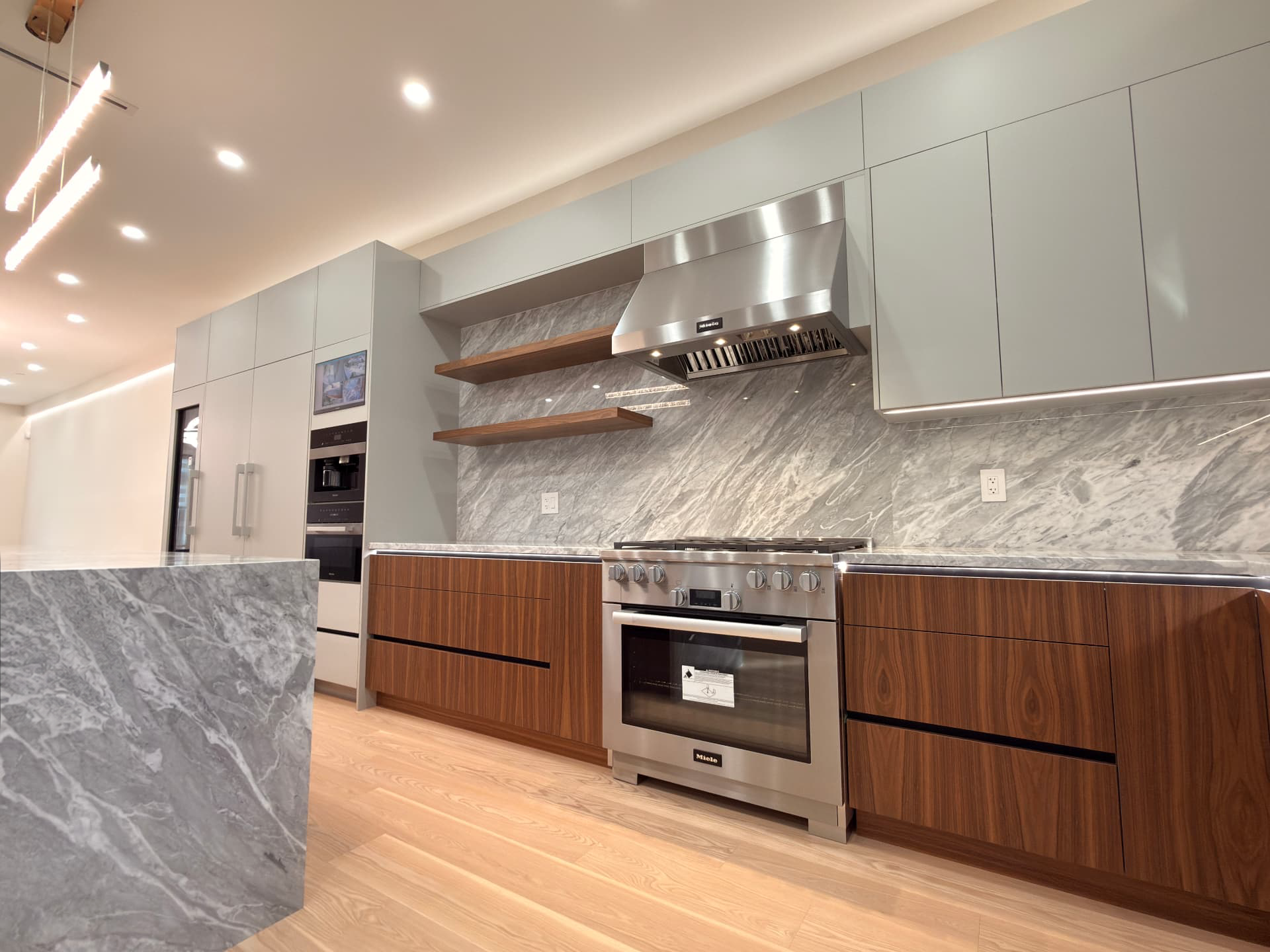 Custom grey and walnut kitchen with a marble island by A Plus Cabinets