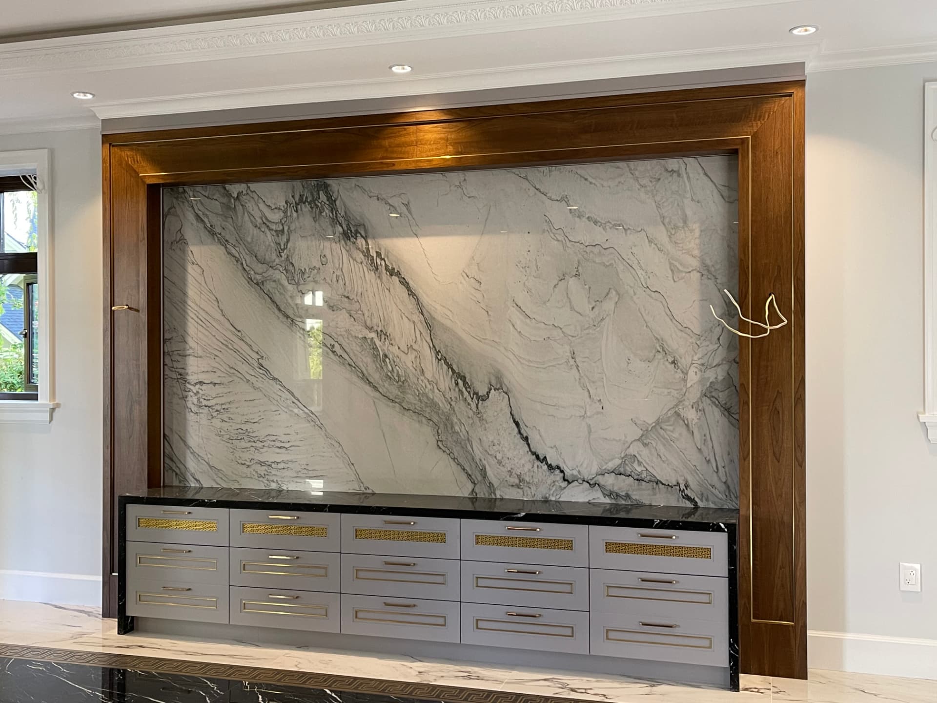 Luxury walnut millwork with book-matched marble feature walls, coffered ceilings, and brass inlay details